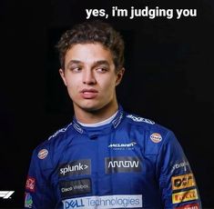 a man in a blue racing suit is looking at the camera and has words written on his chest