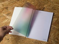 a hand holding an open book on top of a wooden floor