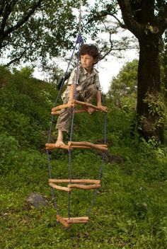 a young boy on a wooden ladder in the grass