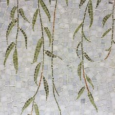 a mosaic tile wall with green leaves on it