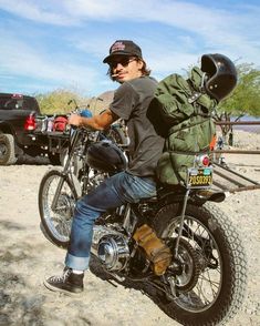 a man riding on the back of a motorcycle with a backpack strapped to it's back