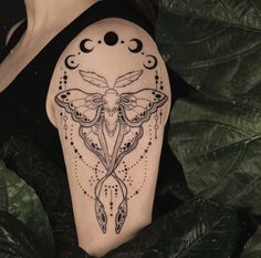 a woman's arm with a moth and moon tattoo on the left side of her body