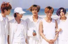 four young men standing next to each other on the beach