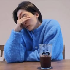 a woman sitting at a table with a drink in front of her and looking bored