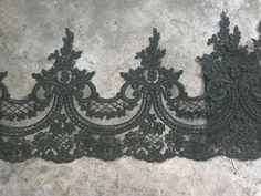 an image of black lace with flowers on the bottom and back side that is cut in half