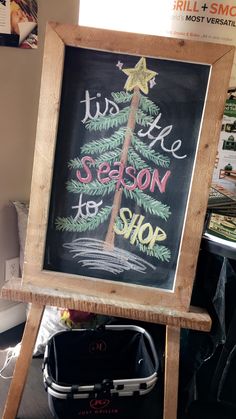 a chalkboard sign that says it's the season to shop with a christmas tree on it