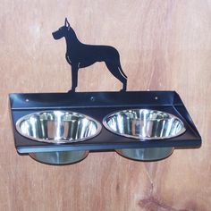 a dog is standing on top of a wall light with two bowls in front of it