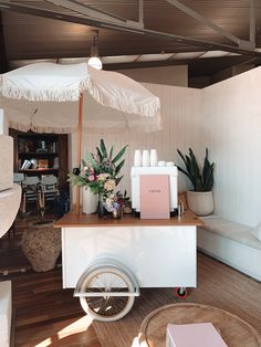 a white cart with an umbrella on top of it in a room filled with furniture