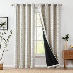 a living room with white and black curtains, a plant on the side of the window