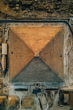 an aerial view of a large pyramid in the middle of a dirt field with buildings around it