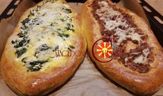 two pizzas with cheese and spinach on them in a cardboard box next to each other