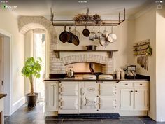 a kitchen with white cabinets and black tile flooring, pots and pans hanging from the ceiling