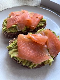 two pieces of bread topped with avocado and salmon