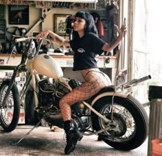 a woman in fishnet stockings sitting on a motorbike and posing for the camera