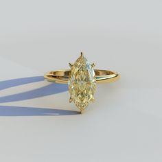 an oval shaped diamond ring on a white surface with shadow from the side, set in yellow gold plating