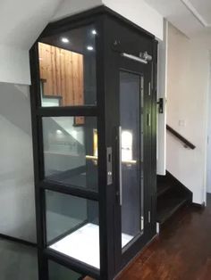 an empty room with a glass case in the center and stairs leading up to it