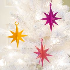 three paper stars hanging from a white christmas tree