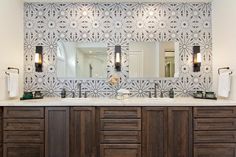 a bathroom with two sinks, mirrors and lights on the wall above them is shown