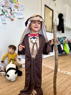 a little boy dressed in a costume holding a stick