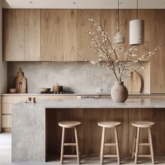 a kitchen with marble counter tops and stools next to a vase filled with flowers