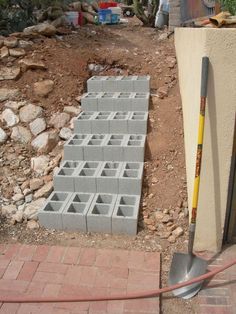 a pile of cinder blocks sitting on top of a brick floor next to a shovel