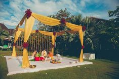 an outdoor wedding setup with yellow drapes and flowers