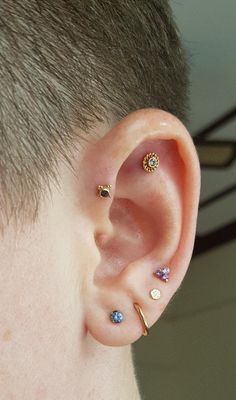 a man with three different colored stones on his ear and one is wearing a gold cartilage