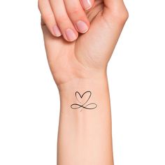 a woman's arm with a small heart tattoo on her left wrist and the word love written in cursive writing