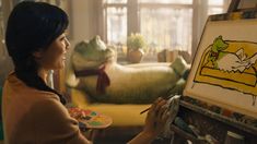 a woman is painting on an easel in her living room