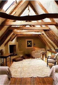 an attic bedroom with wooden floors and exposed ceiling beams, white sheepskin rugs on the floor