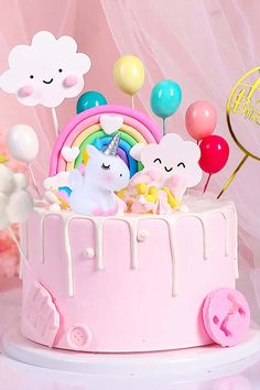 a pink cake with unicorns and balloons on it's top is sitting on a table