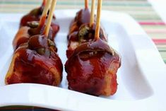 bacon wrapped in ketchup and topped with toothpicks on a white plate