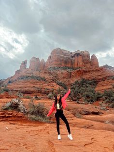 a woman standing in the desert with her arms outstretched