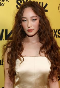 a young woman with long red hair wearing a white dress and posing for the camera