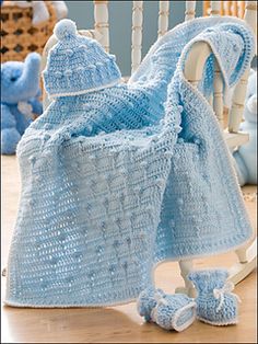 a crocheted baby blanket and booties on a rocking chair