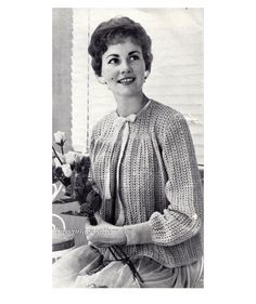 an old black and white photo of a woman holding a flower in her hand, smiling