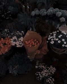 a woman standing in front of a bunch of flowers next to baskets filled with flowers