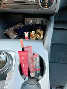 the inside of a car with lipstick and other items in its holder on the dashboard