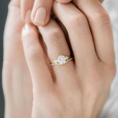 a woman's hand with a diamond ring on top of her finger and the other hand holding an engagement ring