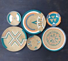 four woven baskets with designs on them sitting on a black surface, one is blue and the other is orange