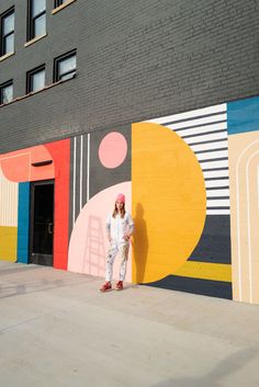 a woman standing in front of a colorful wall