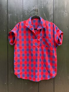 - 1980s navy and red checked camp shirt - Vintage, no tag, feels like a poly-cotton blend - Best fit for a Medium, measures 21" across the chest and 25" from shoulder to hem Unsure about fit or condition? Return any item for a full refund - shipping both ways is always free. Plaid Camp Collar Tops With Relaxed Fit, Collared Gingham Tops With Relaxed Fit, Plaid Camp Collar Shirt For Summer, Summer Plaid Camp Shirt With Camp Collar, Plaid Short Sleeve Camp Shirt With Relaxed Fit, Casual Plaid Camp Shirt With Camp Collar, Plaid Relaxed Fit Collared Camp Shirt, Plaid Collared Camp Shirt With Relaxed Fit, Plaid Relaxed Fit Camp Shirt