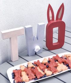 a white plate topped with fruit next to the letters d and person spelled out in red