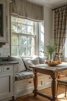 a kitchen table sitting under a window in front of a window seat with pillows on it