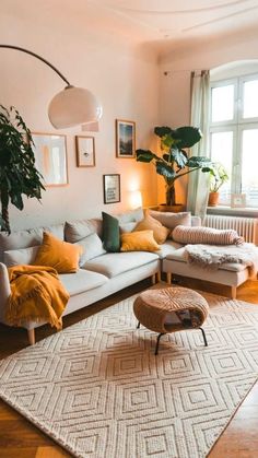 a living room filled with furniture and pictures on the wall next to a rug that has been placed in front of a window