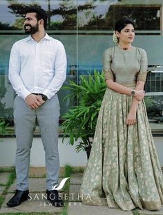 two people standing next to each other in front of a building