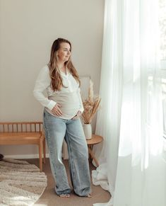 a pregnant woman standing in front of a window