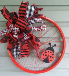 a red bicycle wheel decorated with ladybug and checkered ribbon