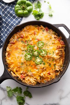 a casserole with cheese and green peppers in a cast iron skillet on a marble countertop