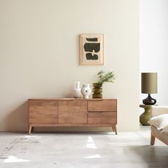 a living room with white walls and wooden furniture in the corner, along with a painting on the wall